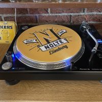 Plattenspieler mit der Nolte-Slipmat. Diese ist gelb und zeigt das 2025er Logo mit dem goldenen N, "Nolte, Lüneburg" und "Yeah"-Pfeilen.